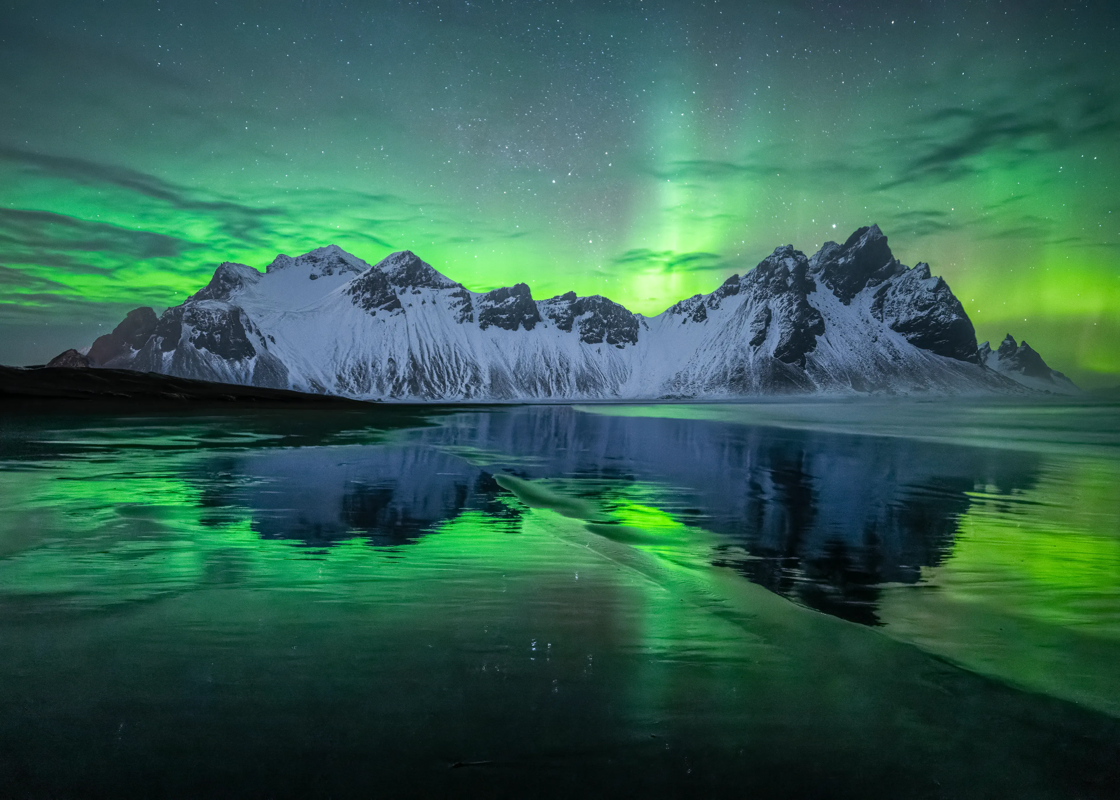 Aurora over Vestrahorn reflecting onto the wet sand